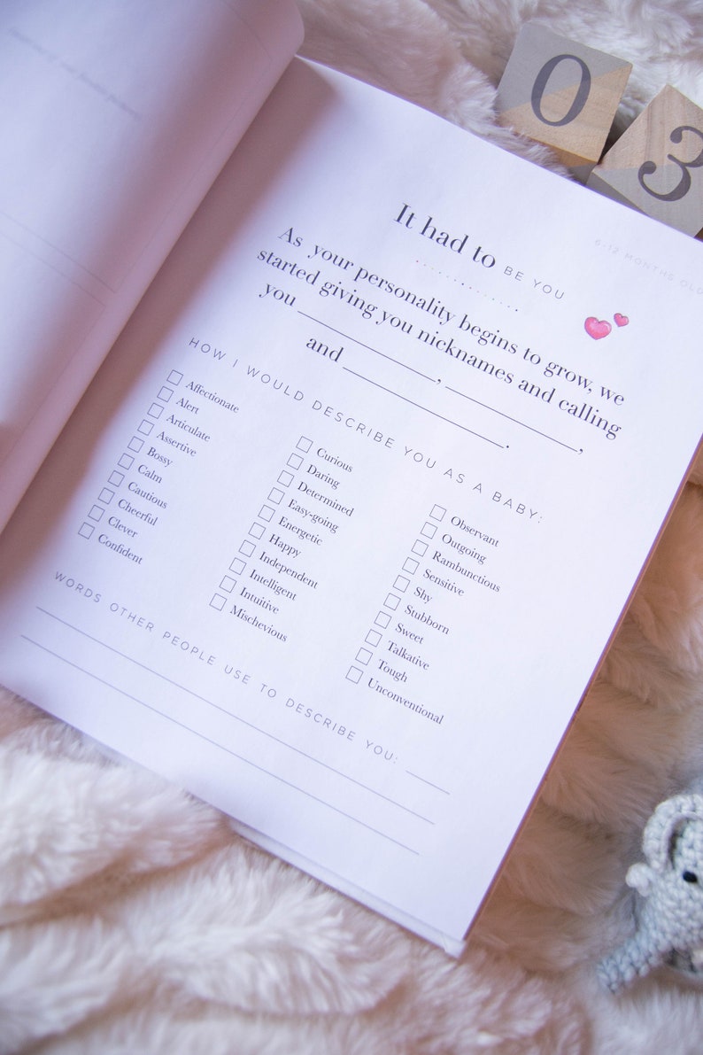 May include: A white page from a baby memory book with a checklist of personality traits. The checklist is titled "How I Would Describe You As A Baby." The traits include "Affectionate", "Alert", "Articulate", "Assertive", "Bossy", "Calm", "Cautious", "Cheerful", "Clever", "Confident", "Curious", "Daring", "Determined", "Easy-going", "Energetic", "Happy", "Independent", "Intelligent", "Intuitive", "Mischevious", "Observant", "Outgoing", "Rambunctious", "Sensitive", "Shy", "Stubborn", "Sweet", "Talkative", "Tough", and "Unconventional".