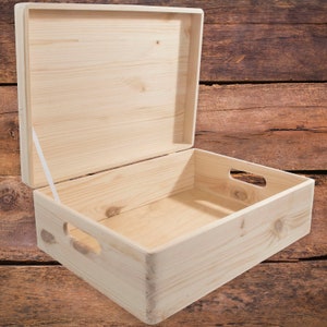 May include: A natural wood storage box with a hinged lid and two cut-out handles on the sides. The box is open and empty.