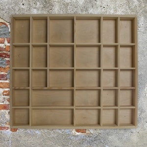 May include: A wooden display shelf with 18 square compartments. The shelf is made of light brown wood and has a simple, rustic design.