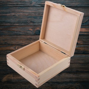 May include: A wooden box with a hinged lid and a brass latch. The box is open and empty, revealing the interior.