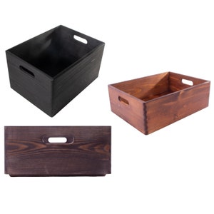 Puede incluir: Tres cajas de almacenamiento de madera con asas. Una caja es negra, una es marrón y una es de un tono marrón más oscuro.