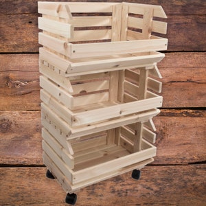 May include: A three-tier wooden rolling cart with a natural finish. The cart has three open shelves and is made of unfinished pine wood. The cart has four black wheels.