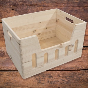 Puede incluir: Una cama para mascotas de madera natural con un borde elevado y agujeros de ventilación. La cama está hecha de madera de pino sin terminar y está diseñada para perros o gatos pequeños.