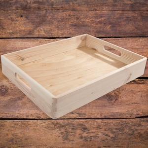 May include: A natural wood tray with two handles on the sides. The tray is empty and sitting on a wooden surface.