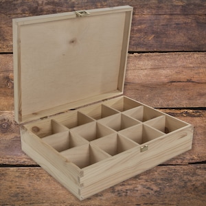 May include: A wooden box with a hinged lid and 12 compartments. The box is made of light-coloured wood and has a natural finish.