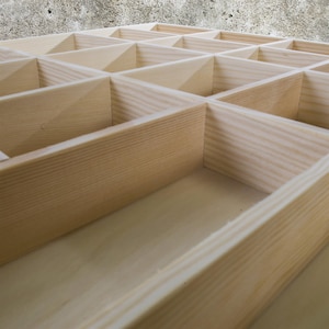 May include: A wooden storage box with multiple compartments. The box is made of light wood and has a natural finish.