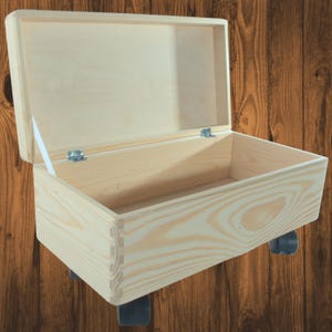 May include: A natural wood storage box with a hinged lid and four wheels. The box is open and empty.
