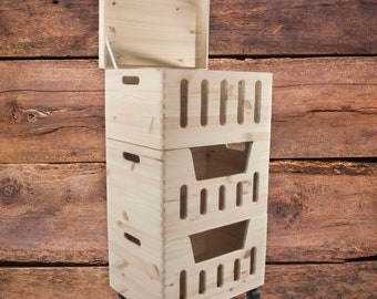 May include: A set of three wooden storage boxes with lids. The boxes are stacked on top of each other and have wheels on the bottom. The boxes are made of natural wood and have a light brown color.