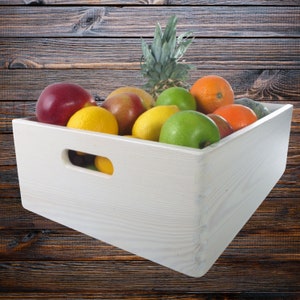 Puede incluir: Una caja de madera blanca llena de una variedad de fruta fresca, incluyendo manzanas, naranjas, limones, limas y una piña.