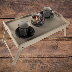 May include: A wooden breakfast tray with two black and white striped mugs, a bowl of chocolate candies, and a white background.