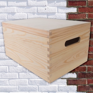 May include: A natural wood storage box with a hinged lid and a cut-out handle. The box is made of unfinished pine wood and has a rectangular shape.