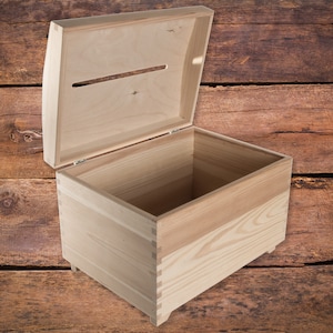 May include: A wooden box with a hinged lid and a slot in the top. The box is open and empty, revealing the interior.