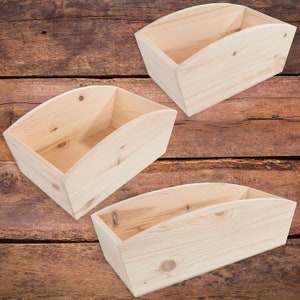 Op de afbeelding: Drie houten dozen met een gebogen bovenrand. De dozen zijn gemaakt van natuurlijk hout en zijn leeg.