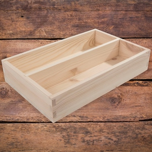 Op de afbeelding: Een natuurlijke houten doos met twee compartimenten, perfect voor het organiseren van kleine items. De doos is gemaakt van onbehandeld hout en heeft een rustieke uitstraling.
