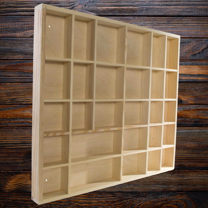 May include: A wooden display shelf with 24 individual compartments. The shelf is made of light-colored wood and has a natural finish.