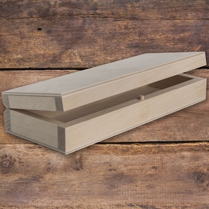 Può includere: Una semplice scatola di legno con un coperchio incernierato, aperta per rivelare l'interno vuoto. La scatola è realizzata in legno chiaro e ha una finitura naturale.
