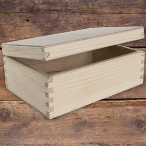 May include: A natural wood box with a hinged lid. The box is open and empty, revealing the natural wood grain.