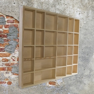 May include: A natural wood display shelf with 24 individual compartments. The shelf is made of unfinished wood and has a rectangular shape.