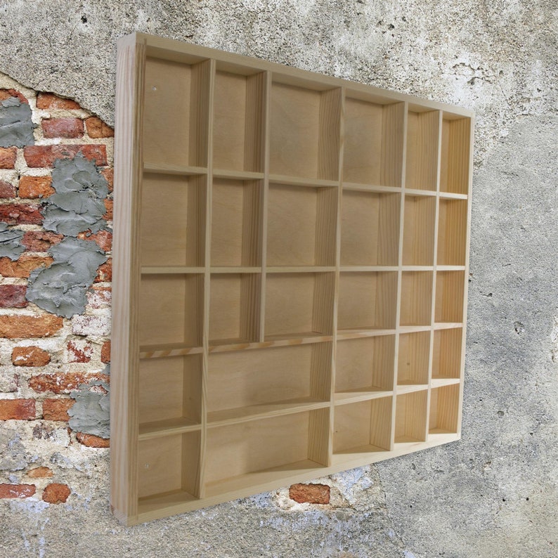 May include: A natural wood display shelf with 24 individual compartments. The shelf is made of unfinished wood and has a rectangular shape.
