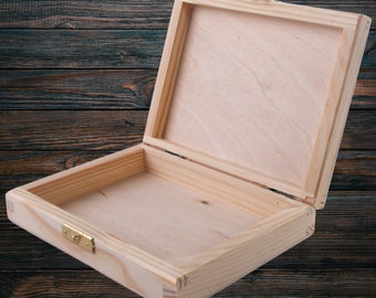 May include: An empty wooden box with a hinged lid and a brass latch. The box is made of light-colored wood and has a natural finish.