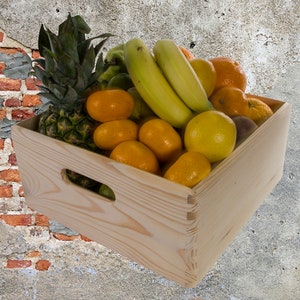 May include: A wooden crate filled with fresh fruit, including a pineapple, bananas, oranges, and a grapefruit. The crate is made of natural wood and has a handle on the side.
