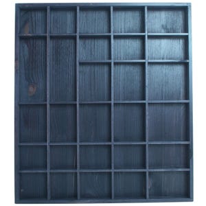 May include: A dark blue wooden display case with multiple square compartments. The wood grain is visible, and the case is likely used for organizing small items or collectibles. The design is simple and functional.