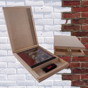 May include: Two wooden boxes with lids. The larger box has a red and black book inside and a black USB drive in the bottom compartment. The smaller box has a latch on the front.