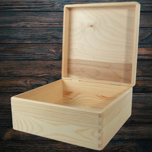 May include: A wooden box with the lid open, revealing the empty interior. The box is made of light-coloured wood and has a natural finish.