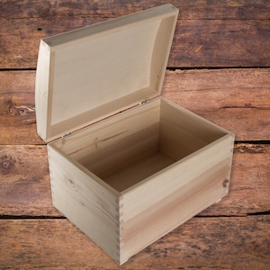 May include: An empty wooden box with a hinged lid. The box is made of light-colored wood and has a natural finish. The lid is open and the inside of the box is visible.