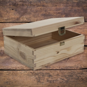 May include: A wooden box with a hinged lid and a brass latch. The box is made of unfinished pine wood and has a natural wood grain.