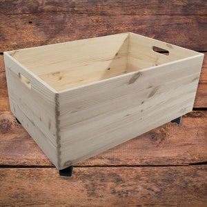 May include: A natural wood storage box with two handles on the side and four black wheels on the bottom. The box is empty and sitting on a wooden surface.