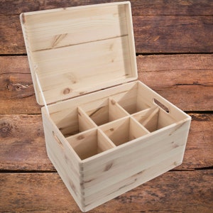 May include: A wooden box with a hinged lid and six compartments. The box is made of light-colored wood and has a natural finish.