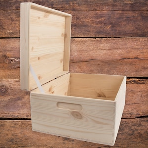 May include: An empty wooden box with a hinged lid and a handle on the front. The box is made of light-coloured wood and has a natural finish.