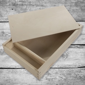 May include: A wooden box with a hinged lid and a smaller compartment inside. The box is made of natural wood and has a light brown color.