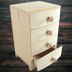 May include: A small wooden dresser with four drawers and rounded edges. The dresser is made of light wood and has simple wooden knobs.