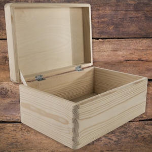 May include: An empty wooden box with a hinged lid. The box is made of light-coloured wood and has a natural finish. The lid is open and the box is sitting on a wooden surface.
