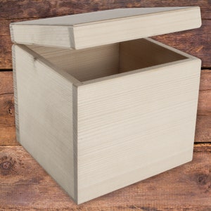 May include: A plain wooden box with the lid open. The box is made of light-coloured wood and has a smooth finish.