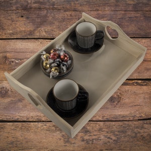 Peut inclure: Un plateau en bois avec deux tasses à café et soucoupes rayées noir et blanc, et un bol de chocolats assortis. Le plateau a une découpe en forme de cœur de chaque côté.