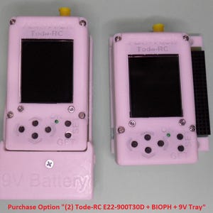 May include: Two white plastic devices with black buttons and a small green LED light. The devices have a small screen and the text "Tod-RC" printed on them. The text "9V Battery" is printed on the bottom of the device on the left. The text "Purchase Option (2) Tode-RC E22-900T30D + BIOPH + 9V Tray" is printed below the devices.