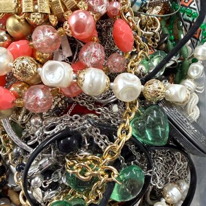 May include: A collection of assorted necklaces and jewelry. The image features gold, silver, and black chains, along with beads in shades of red, pink, white, and green. Some necklaces have heart-shaped pendants.