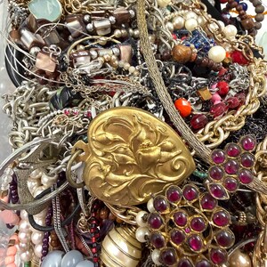 May include: A collection of various jewelry pieces, including necklaces, bracelets, and earrings. The assortment features gold, silver, and beaded strands, with accents of pearls, gemstones, and ornate pendants. A variety of colors and textures are visible.