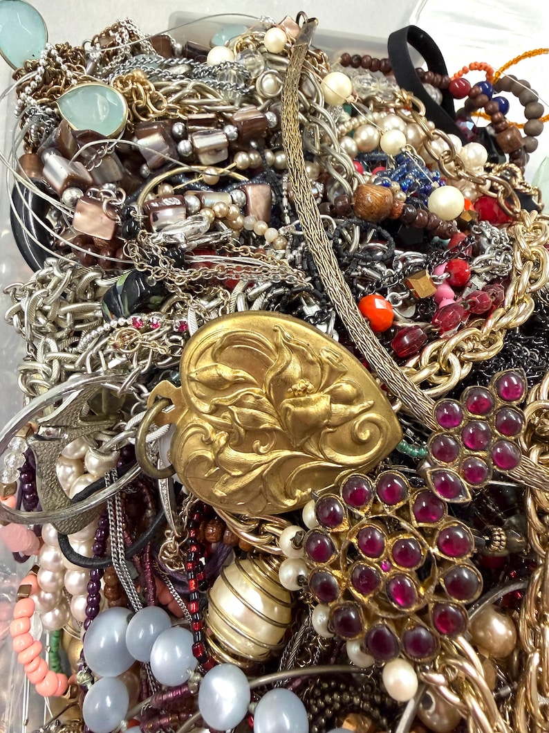 May include: A collection of various jewelry pieces, including necklaces, bracelets, and earrings. The assortment features gold, silver, and beaded strands, with accents of pearls, gemstones, and ornate pendants. A variety of colors and textures are visible.
