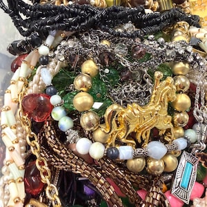 May include: A collection of various necklaces and jewelry pieces. The image features gold, silver, and beaded necklaces, along with pendants and bracelets. Colors include gold, silver, black, red, and white.