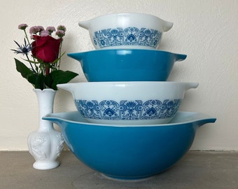 May include: A set of four blue and white mixing bowls with a floral pattern. The bowls are stacked on top of each other, with the largest bowl at the bottom and the smallest bowl at the top.