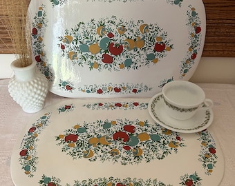 May include: Two white oval serving trays with a floral design featuring red, yellow, and green leaves and fruit. The trays are made of a hard plastic material and have a glossy finish.