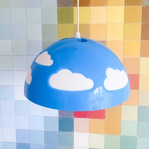 Puede incluir: Una lámpara de techo azul y blanca con forma de nube. La lámpara tiene un cable blanco y una montura de techo blanca.