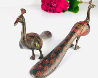 Puede incluir: Dos figuritas decorativas de pavo real con detalles intrincados. Los pavos reales están hechos de metal y tienen un acabado marrón oscuro con acentos rojos, verdes y dorados. Las plumas de la cola están extendidas y tienen un diseño estampado.