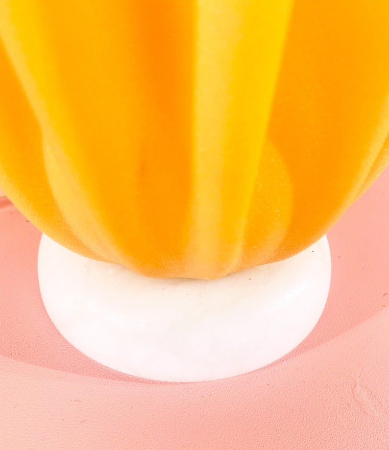 May include: A bright yellow ceramic pumpkin with a white base. The pumpkin has a smooth, rounded shape and a slightly textured surface.