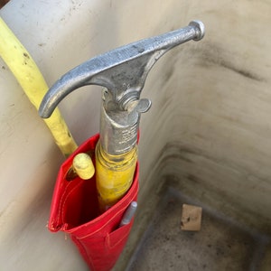 May include: A red tool bag with a yellow and silver tool inside. The tool has a hook on the end and a handle with a knob.