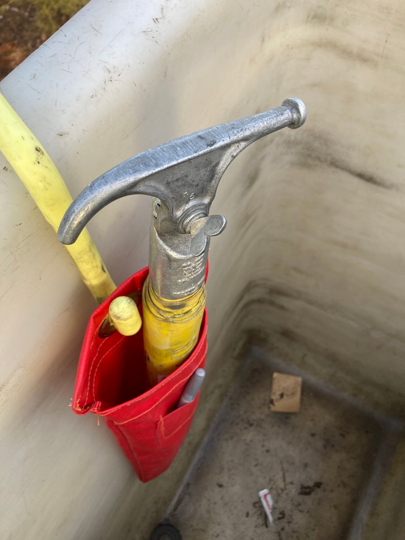 May include: A red tool bag with a yellow and silver tool inside. The tool has a hook on the end and a handle with a knob.
